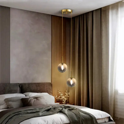 Two spherical frosted white and smoke gray globe pendant lights with gold-toned metal fixtures for dining room