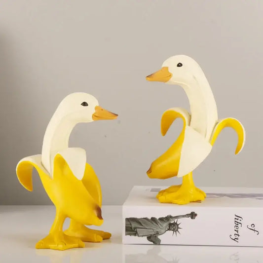 Two white duck figurines with yellow beaks and feet designed as a funny banana duck sculpture for living room decor