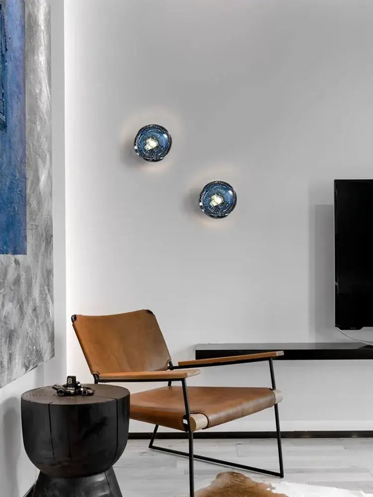 Two circular blue glass wall sconce lamps with textured reflective surfaces for living room lighting
