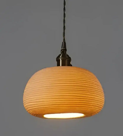 Geometric amber and cream glass pendant light with warm-toned ribbed ceramic and brass metal fixture for dining room