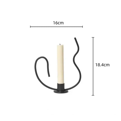 Geometric black metal candlestick candelabrum with curved wrought iron design holding an off-white candle centerpiece