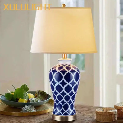 Blue ceramic bedside table lamp with white geometric pattern, gold-toned base, and cream fabric shade for bedroom