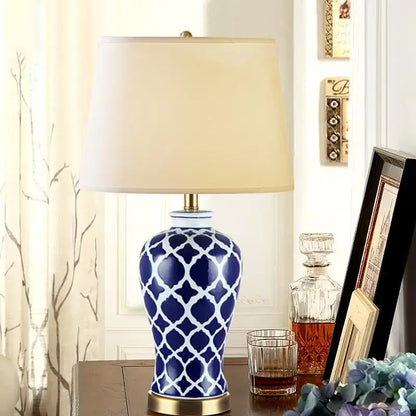Blue and white patterned ceramic table lamp with cream fabric shade and gold base for bedside table use