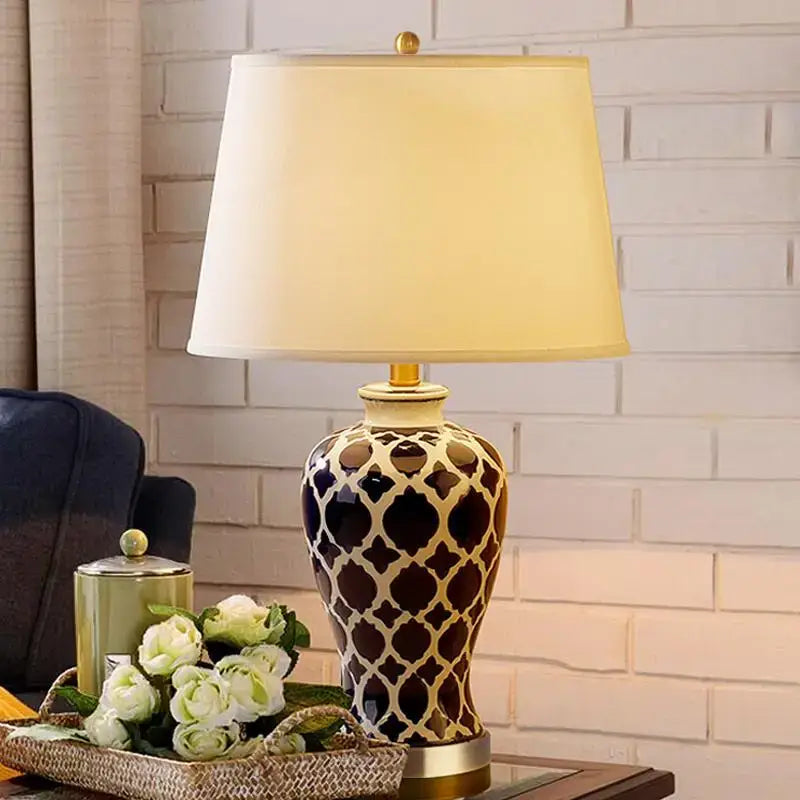 Decorative blue ceramic table lamp with black and cream geometric pattern and beige fabric shade for bedside table