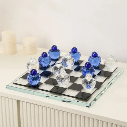 A geometric blue and clear glass chess set with faceted pieces on a black and white checkered glass board