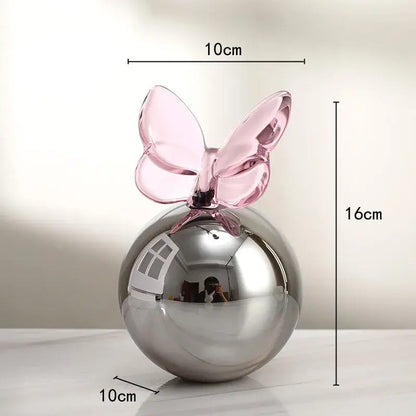 A geometric butterfly crystal ball with a sleek silver sphere and translucent pink glass butterfly for home decor