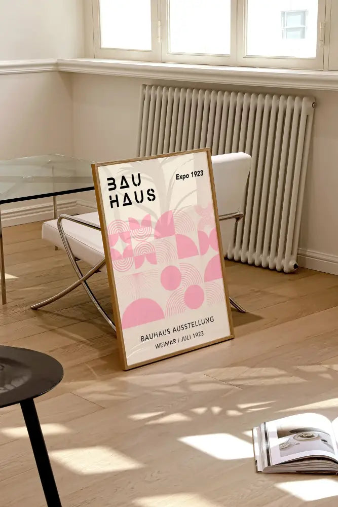 A framed DecorBites™ bauhaus geometric canvas print with pink patterns and black text in light wood frame for home decor