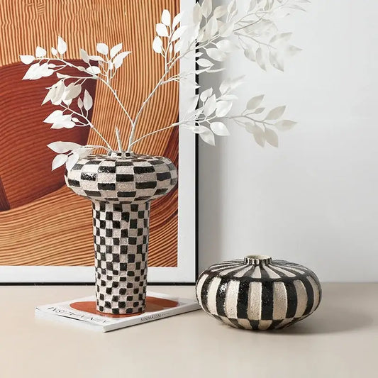 Black and white geometric check ceramic vase with flared top beside a matching striped ceramic container decorbites geometric check