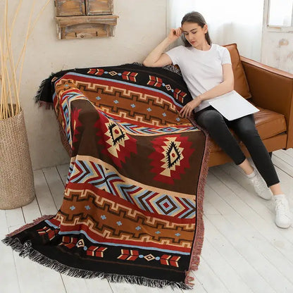 A cozy brown red and beige decorbites geometric cotton knitted sofa blanket with tribal patterns and fringed edges