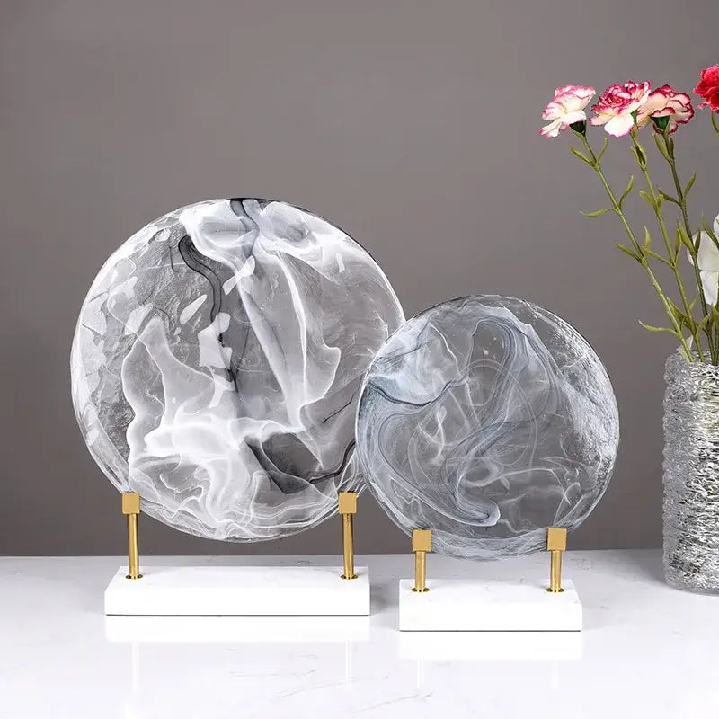 Two elegant translucent geometric disk marble spheres with gray and white patterns on gold stands for home decor