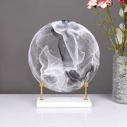Geometric disk marble clear glass orb with swirling black and white patterns on white marble base for home decor