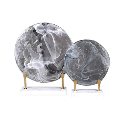 Two gray and white marbled geometric disk marble orbs on gold-toned stands for elegant home decor accents