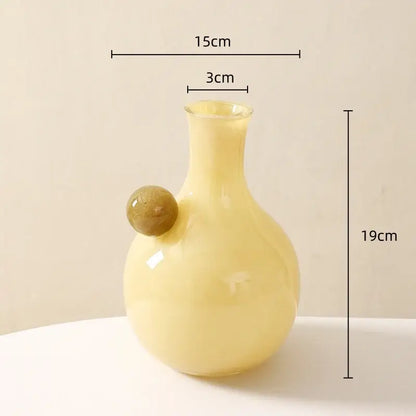 A pale yellow glossy glass sphere vase with an amber geometric glass sphere accent for decorbites geometric glass decor