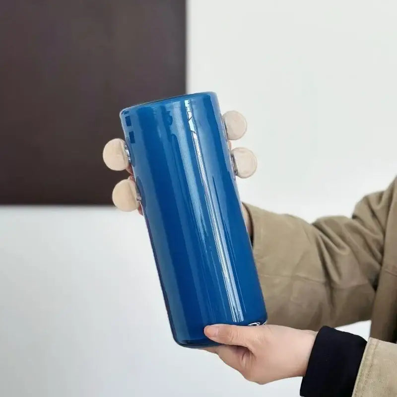 A sleek royal blue cylindrical water bottle with minimalist design shown alongside decorbites geometric glass vase with color patches
