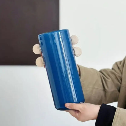 A sleek royal blue cylindrical water bottle with minimalist design shown alongside decorbites geometric glass vase with color patches