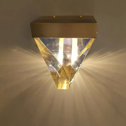 Gold-finished geometric led wall sconce with faceted crystal panels emitting warm light for bedroom decorbites crystal led use