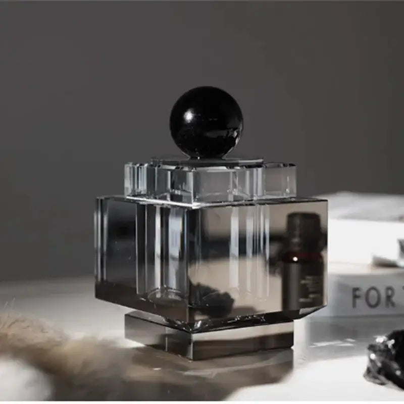Clear crystal perfume bottle with faceted geometric design and glossy black stopper for geometric storage jar use