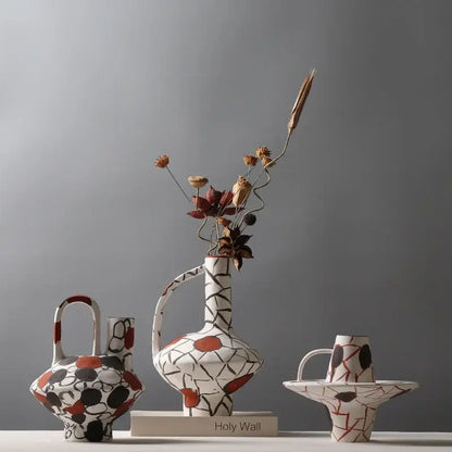 White ceramic geometric graffiti ceramic vase with black terracotta patterns and curved handle holding dried flowers