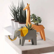 Geometric gray and orange giraffe 3d papercraft planter with yellow accents holding succulents for living room decor