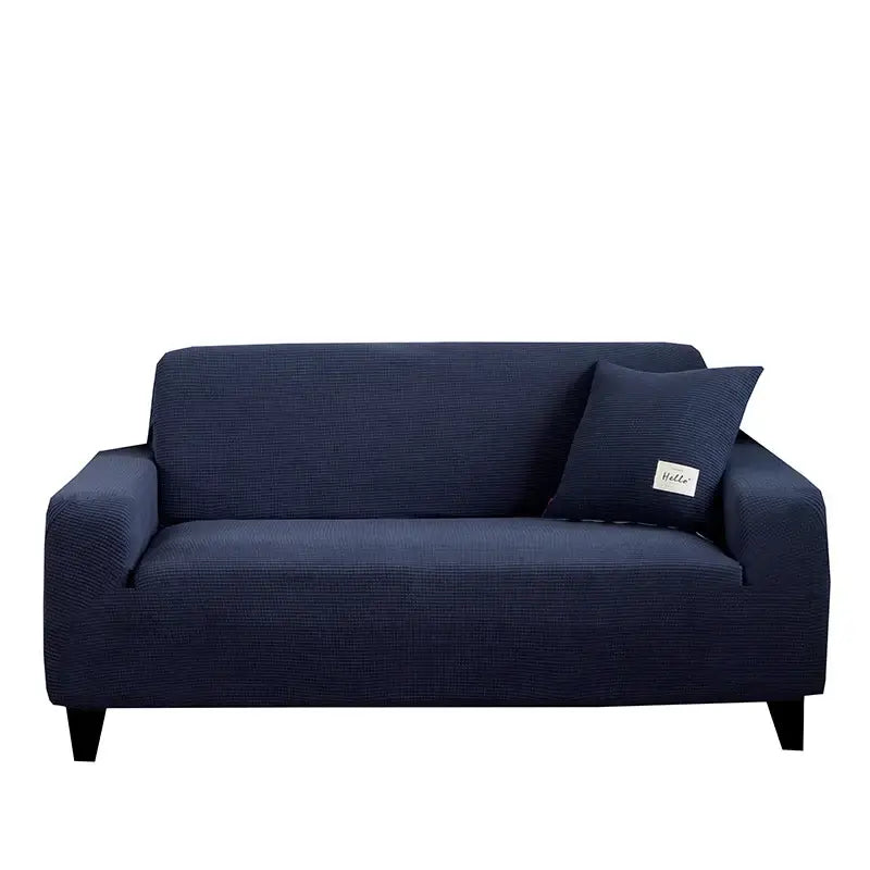 Navy blue textured stretch sofa cover with matching pillow and small white label for living room use