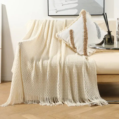 Cream-colored geometric knit sofa blanket with textured tassel fringe for living room decor by decorbites
