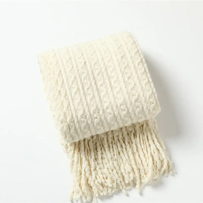 Cream-colored knitted scarf with textured cable pattern and fringe complementing decorbites geometric knit sofa blanket