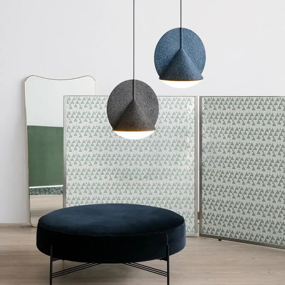 Two modern geometric matte copper and charcoal gray pendant lamps with textured shades hang above a navy ottoman for kitchen decorbites colorful led ceiling lighting