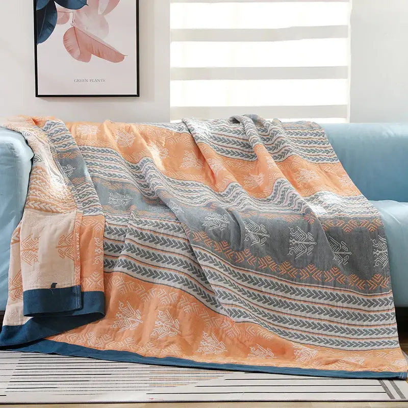 A cozy decorbites cotton gauze summer blanket with vibrant orange and gray geometric quilted design