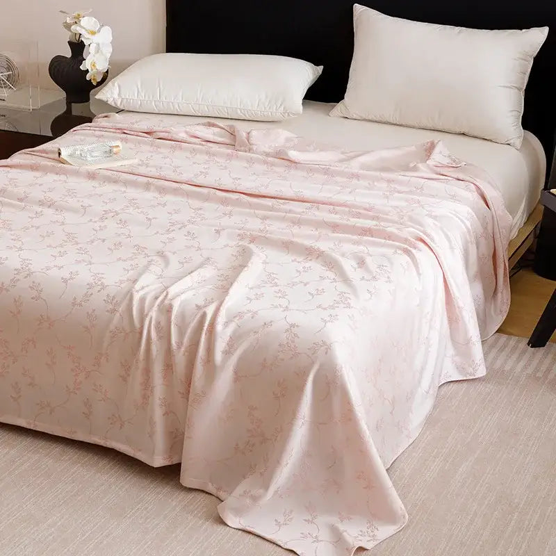 A soft pink satin bedspread with floral pattern draped over mattress in lightweight decorbites bamboo fiber summer bedding