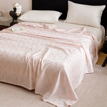 A soft pink satin bedspread with floral pattern draped over mattress in lightweight decorbites bamboo fiber summer bedding