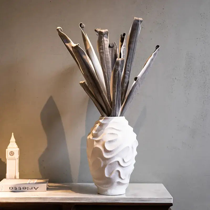 Geometric spiral white ceramic vase with wavy texture holding dried stems for home decor and fruit platter display