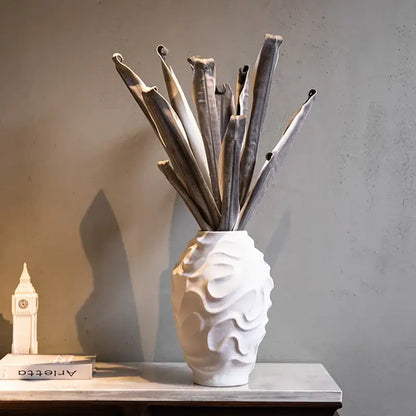 Geometric spiral white ceramic vase with wavy texture holding dried stems for home decor and fruit platter display