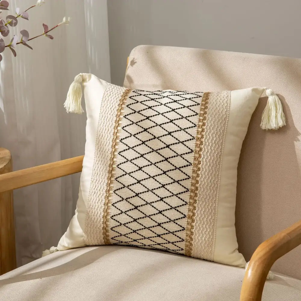 Cream-colored cushion cover with black diamond embroidery and beige trim featuring decorbites geometric tassel accents