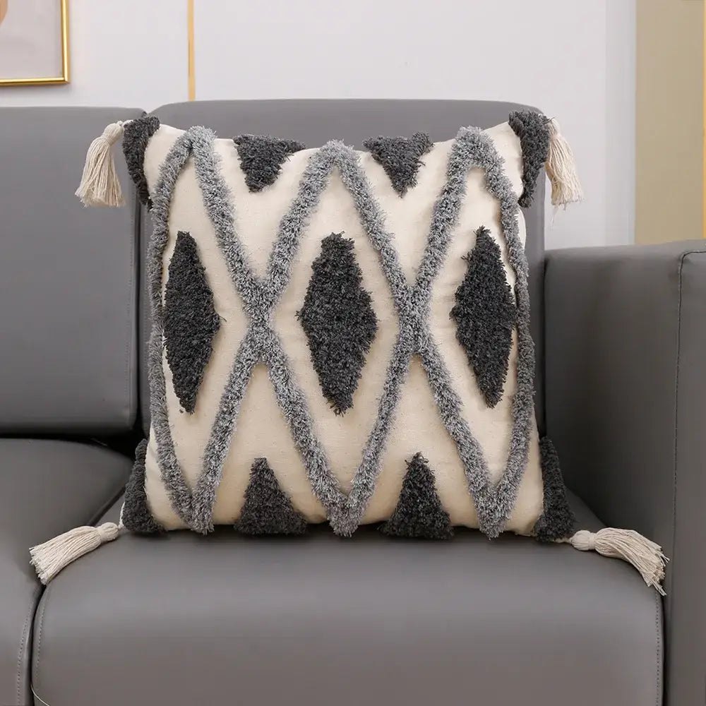 Cream-colored geometric tufted cushion cover with dark and light gray yarns and tassel decorbites geometric tufted accents