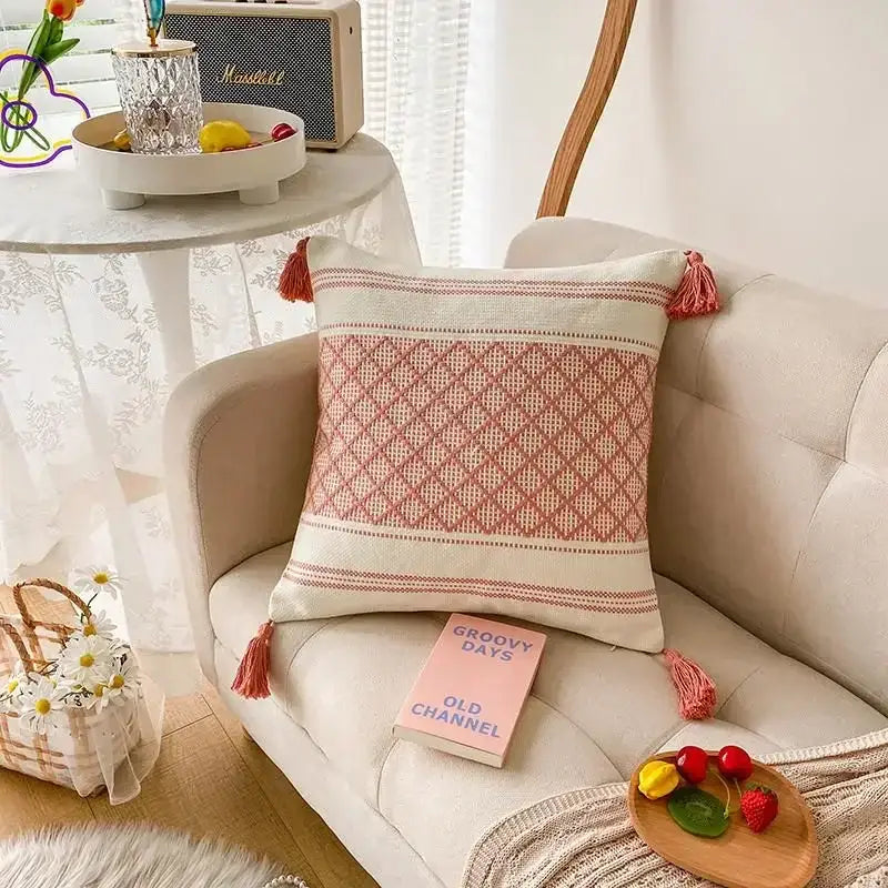 A soft cream cushion cover with woven pink diamond geometric tufted pattern and matching tassels for decorbites decor