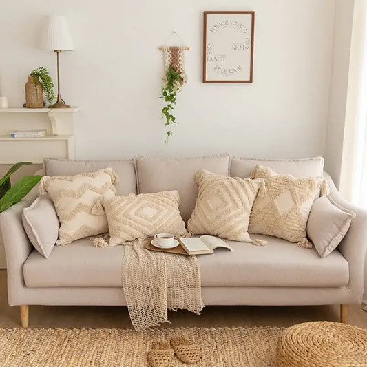 Beige upholstered sofa with decorbites geometric tufted tassel pillowcases in cotton linen and a woven blanket draped