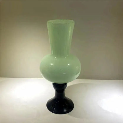 A sleek translucent light green geometric vintage glass vase on a black glossy pedestal base for decorbites geometric vintage decor
