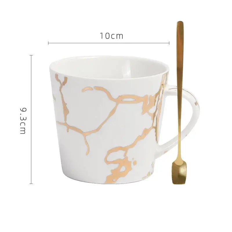 White ceramic cup with gilded marble texture gold patterns and matching gold spoon by decorbites for luxury dining