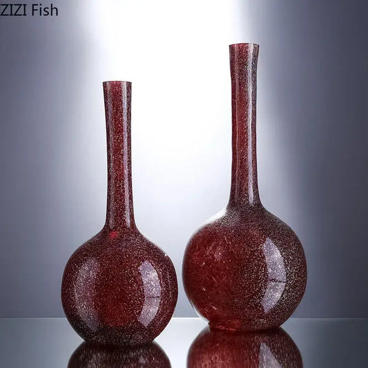 Two elegant gilded red glass vases with a sparkling finish and slender necks featuring artificial flowers decorbites gilded red
