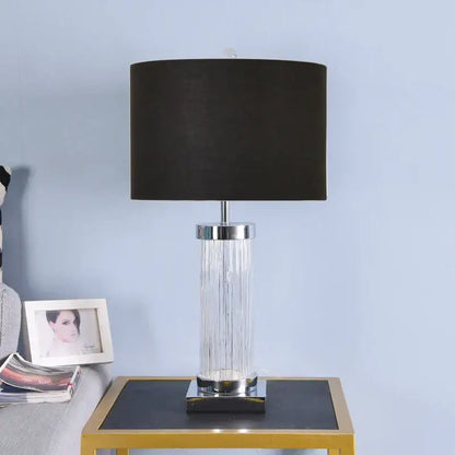 A sleek table lamp with black fabric shade, clear glass crystal cylinder body, and polished chrome accents for bedroom