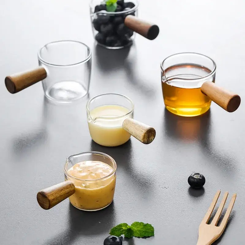 Clear glass espresso measuring cups with wood handles each filled with different colored liquids for kitchen use