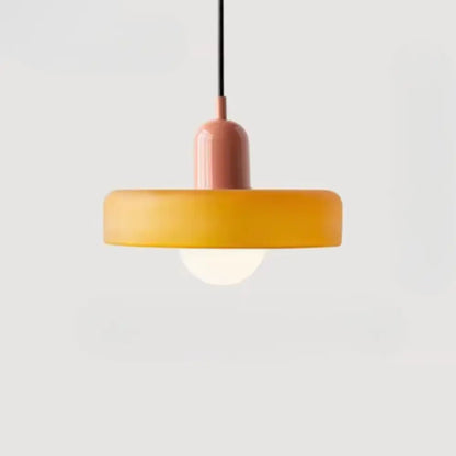 A bauhaus style glass pendant lighting with a matte peach cylindrical stem and amber glass pendant shade suspended by black cord