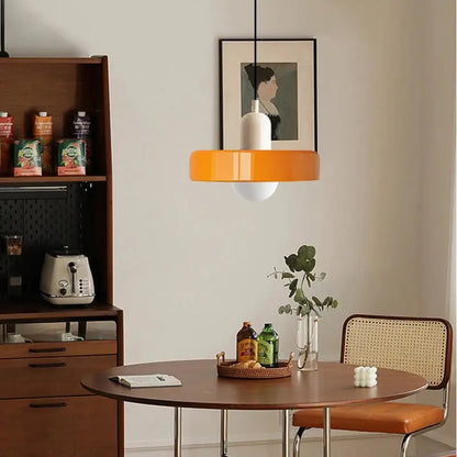 Modern glass pendant lighting with vibrant orange circular glass shade and white cylindrical base suspended by black cord