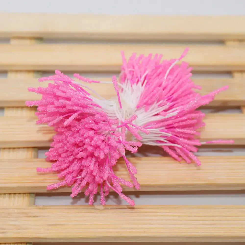 A vibrant pink and white glittery mini flower stamen hair tie with fuzzy spiky texture for kids bedroom use