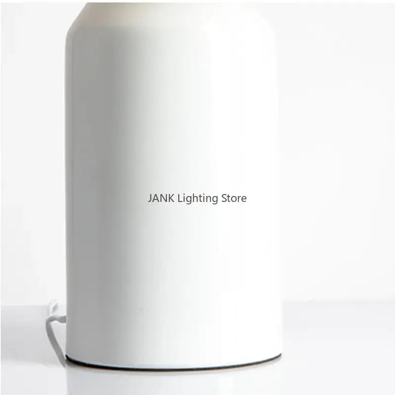 A sleek minimalist white cylindrical table lamp with matte finish and black base perfect for decorbites atollo bedroom use