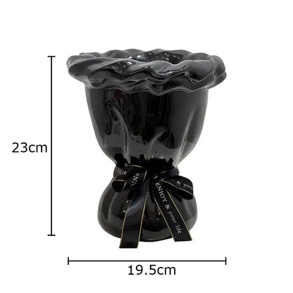 Glossy black ceramic vase with ruffled rim and tied ribbon holding pink artificial flowers for bedroom decorbites decor