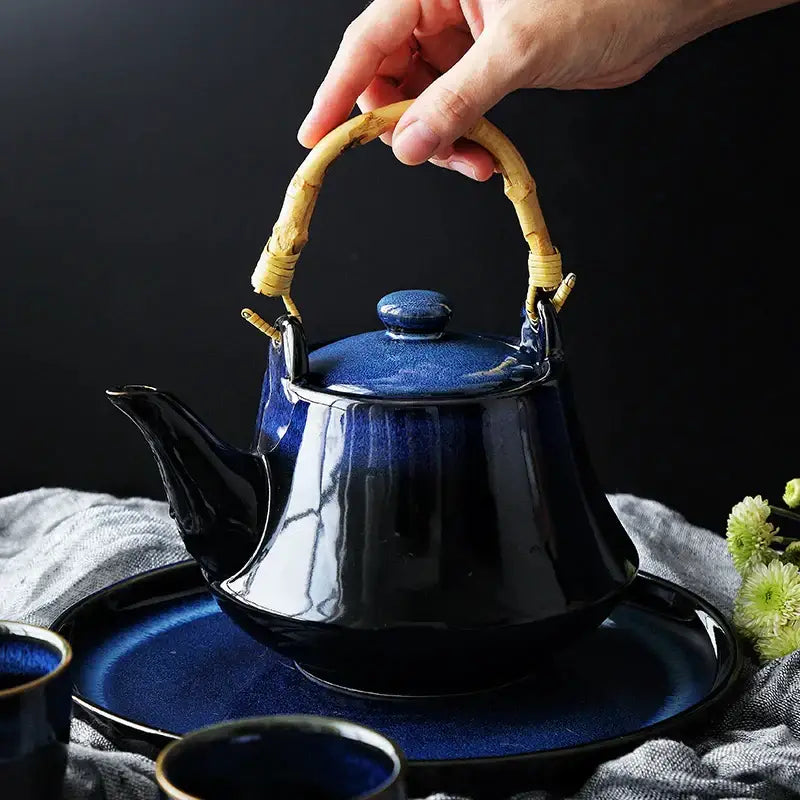 Glossy blue ceramic tea kettle with bamboo handle and matching lid on coordinating saucer for decorbites blue ceramic set
