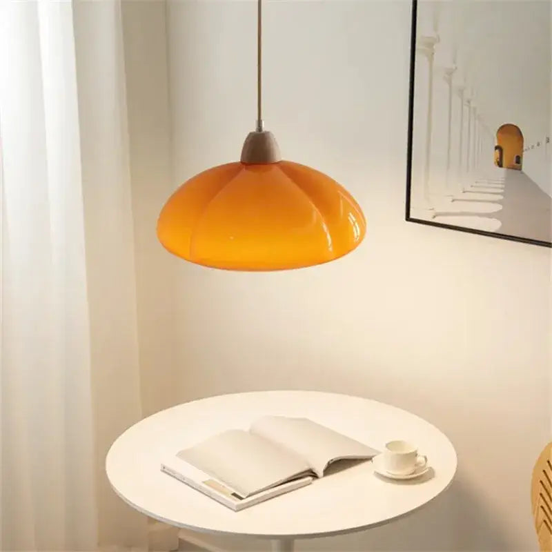A vibrant orange glass pumpkin chandelier with a glossy ceramic finish for bedroom lighting hangs from the ceiling