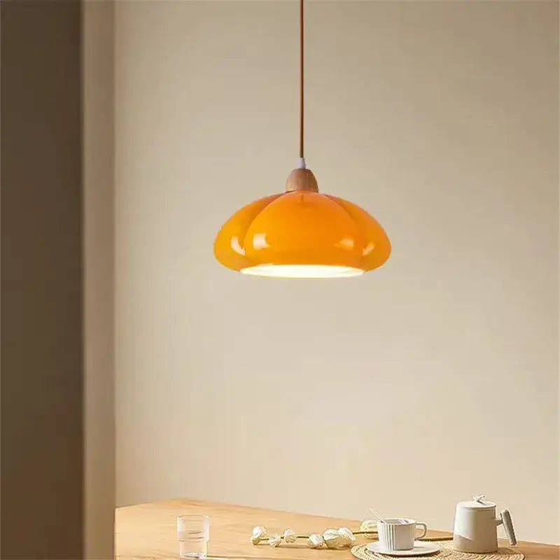 Glossy orange ceramic pumpkin chandelier with wooden top and brown cord for bedroom lighting in warm tones