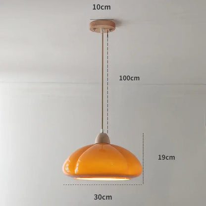 A warm amber glass pumpkin chandelier with wooden mount and metal chain ideal for bedroom or restaurant balcony lighting
